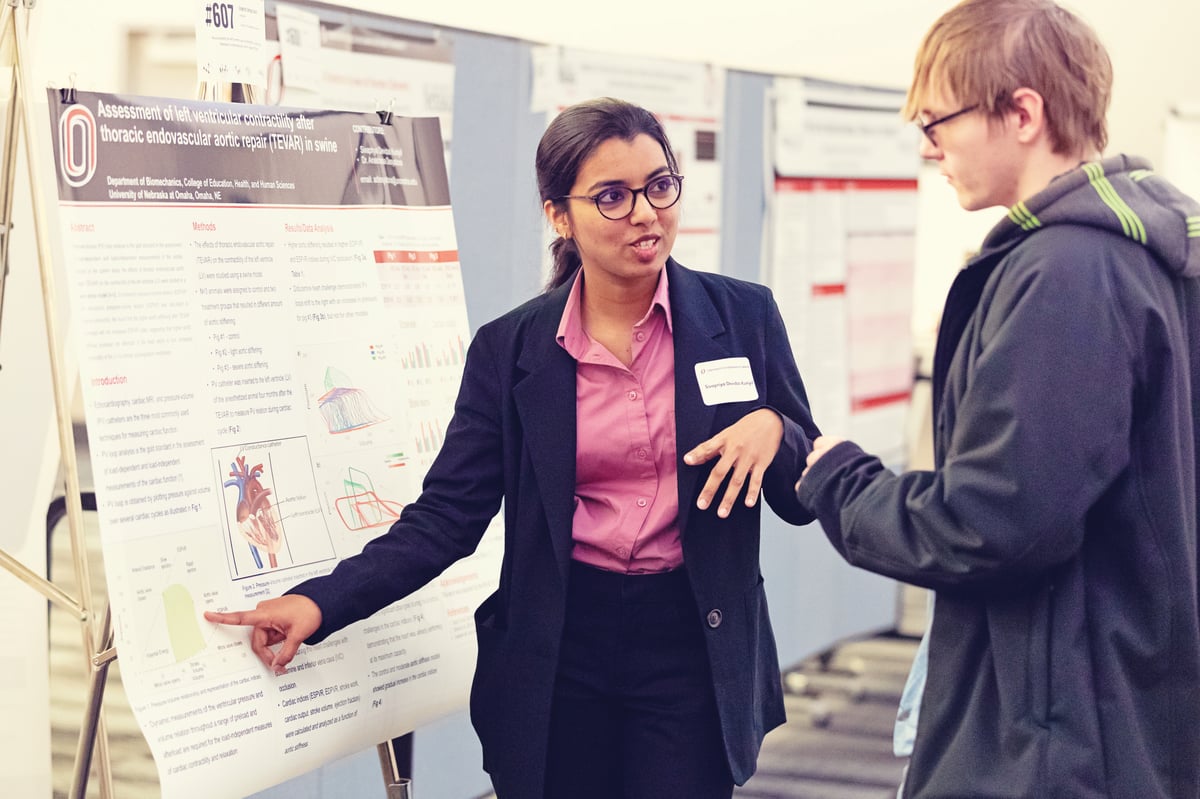 Girl giving a presentation to another person by pointing at a display board