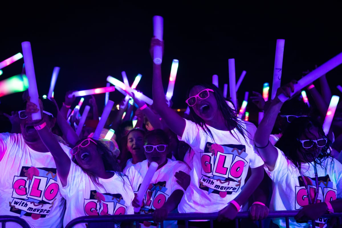 Group of people dancing at a music event at night with glow sticks