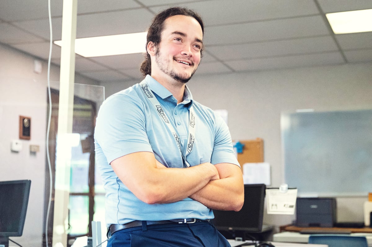 A smiling man with his arms crossed in an office setting