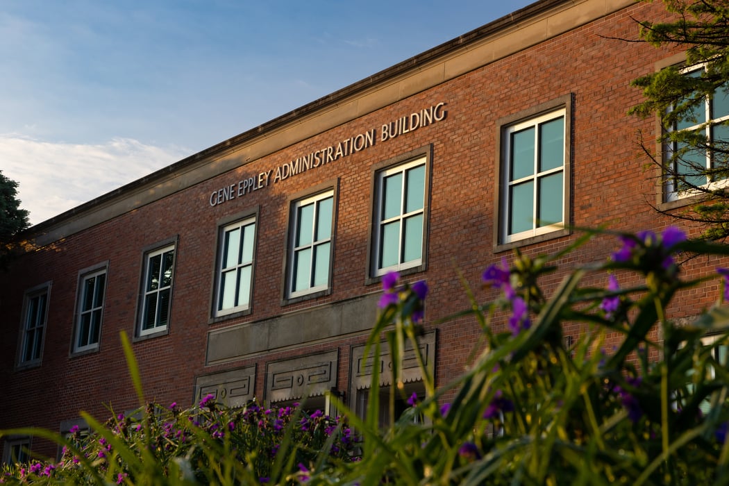 Front of Eppley Administration Building. Purple flower bloom along the bottom of the photo.