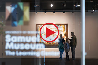 Family looking at painting behind glass door with Samuel Bak Museum: The Learning Center logo on it