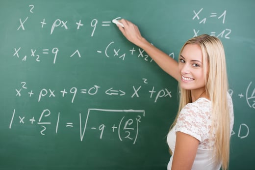 Clever confident female student in the classroom writing on a chalkboard completing mathematical equations-1
