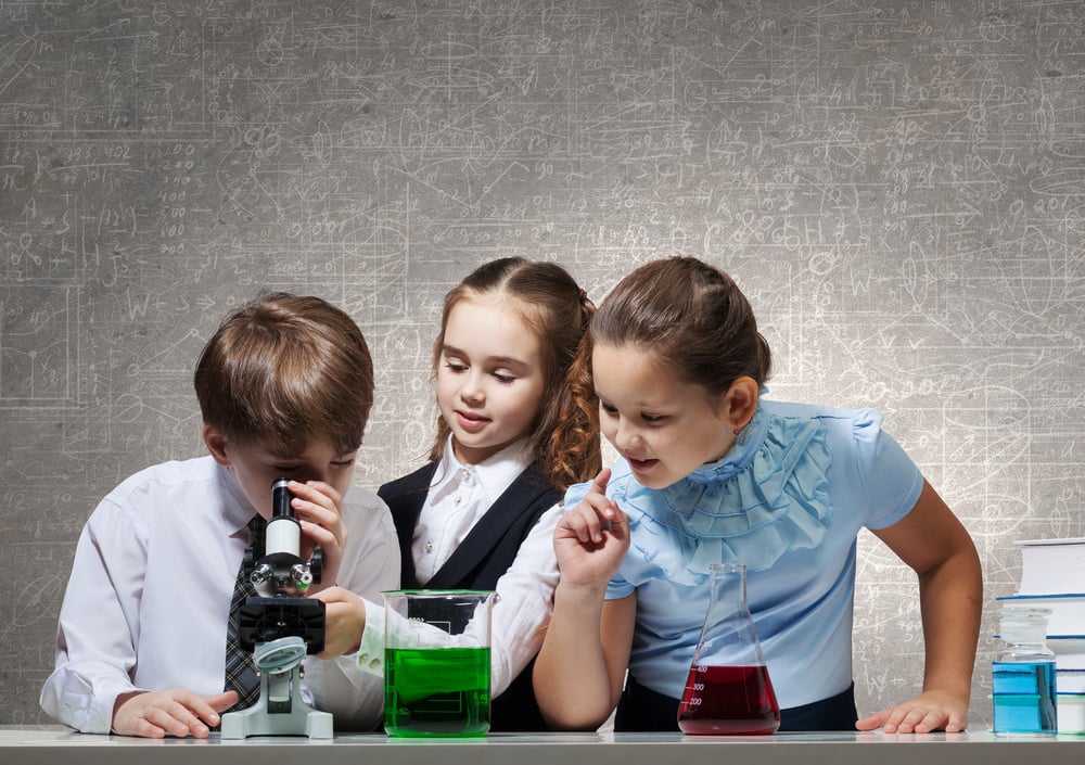 Cute girl and boy at chemistry lesson making tests