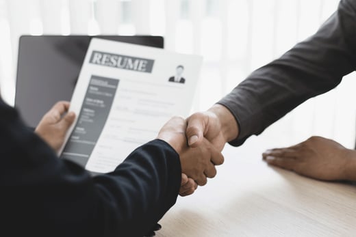 Someone holding a resume while shaking hands with someone else