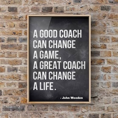 Sign on a brick wall that reads "a good coach can change a game, a great coach can change a life."