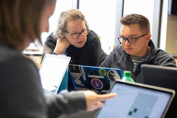 UNO professor Betty Love works with a student on his laptop during her class