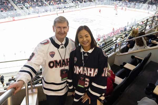 NU President Ted Carter and Chancellor Joanne Li in Maverick hockey jerseys during a game at Baxter Arena