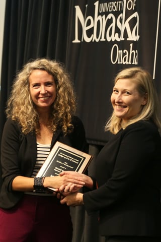 Dean Bloom shakes hands with Dr. Danielle Battisti and hands Dr. Battisti a plaque