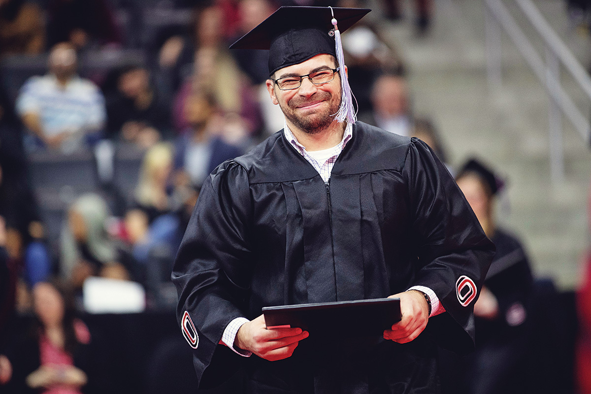 UNO student at graduation holding diploma