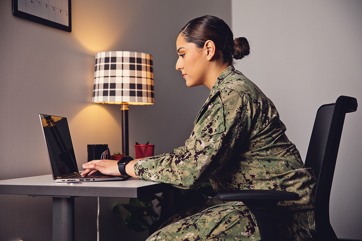 UNO military student researching on a laptop at a desk