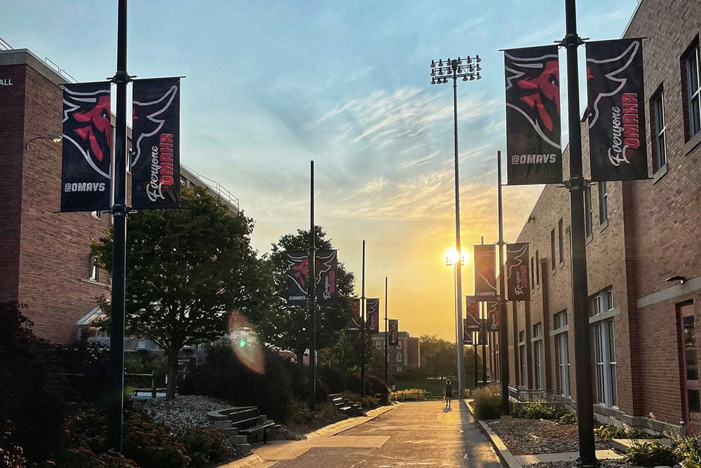 The sun rises between buildings on the UNO campus